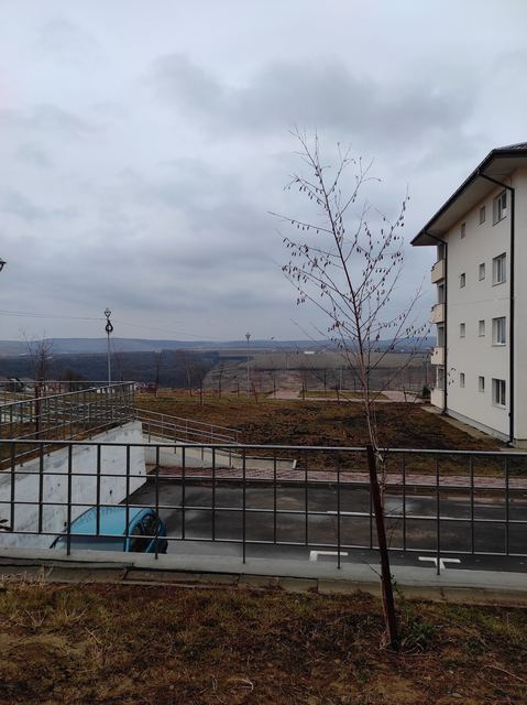 Bloc de locuințe la marginea unei platforme, cu dealuri în fundal