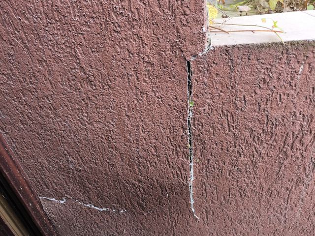 Fisură verticală într-un soclu tencuit, roșu-brun