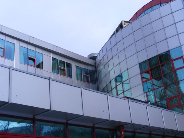Corp de legătură cu fațadă de panouri, alăturat unei fațade curbe vitrate.