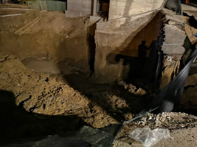 Perete de pământ al excavației lângă fundația de beton a clădirii, noaptea